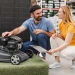The Best Time to Buy a Lawn Mower Happy couple examining new model of lawn mower in an electrical store for gardeners