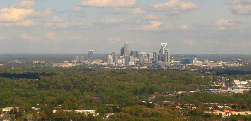 An aerial view of the forest surrounding the skyline of Charlotte, North Carolina