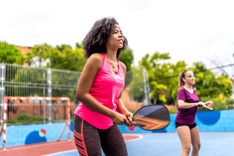 Two women play pickleball outdoors
