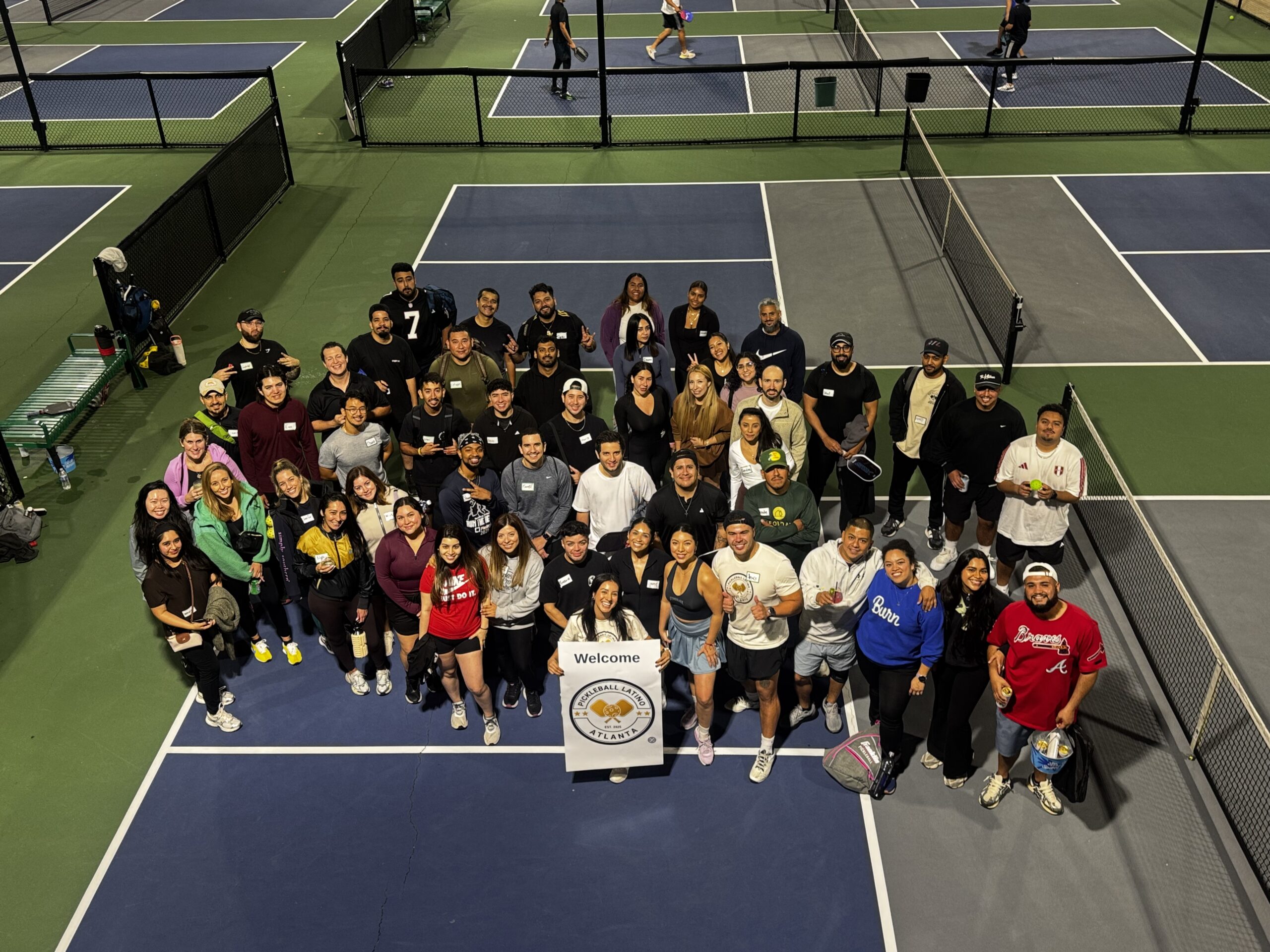 Dozens of pickleball players from PickleLatino smile for a picture at an indoor court in Atlanta 