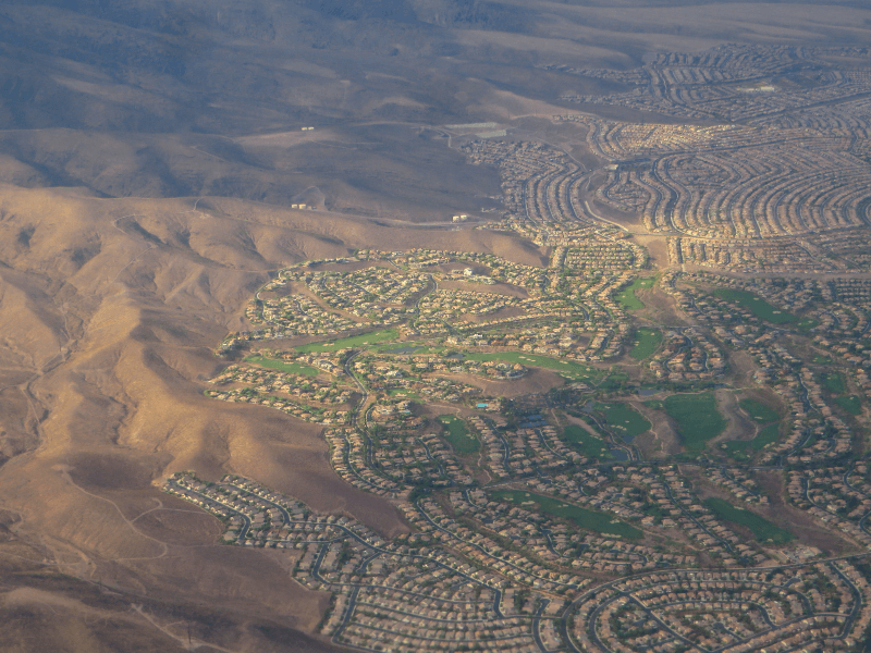 An aerial view of green residential areas of Henderson, Nevada, near a mountain range