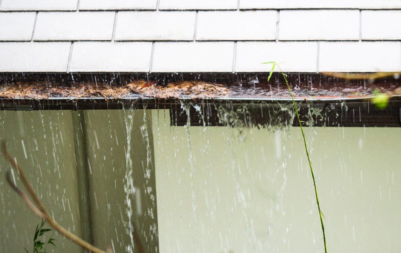 Closeup of a clogged rain gutter overflowing with water during a rainstorm