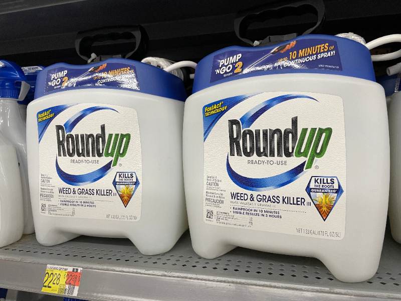Two large 1.33-gallon jugs of Roundup Ready-to-Use Weed & Grass Killer III with Pump 'N Go 2 sprayers sitting on a Walmart store shelf, with a yellow price tag